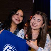 Two grads smile with a GV Alumni t-shirt